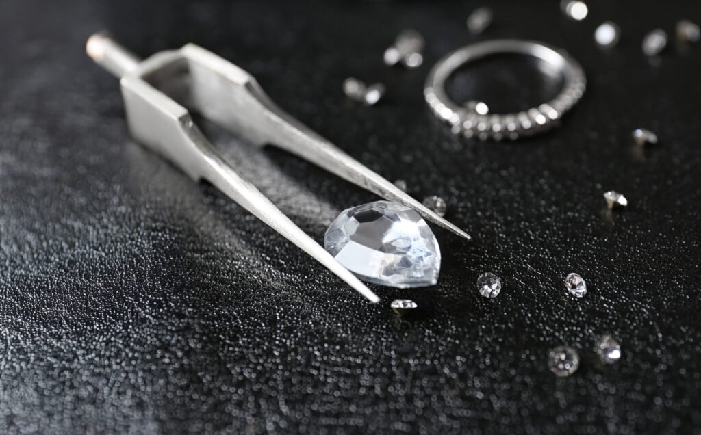 Jewels and tweezers on black leather surface